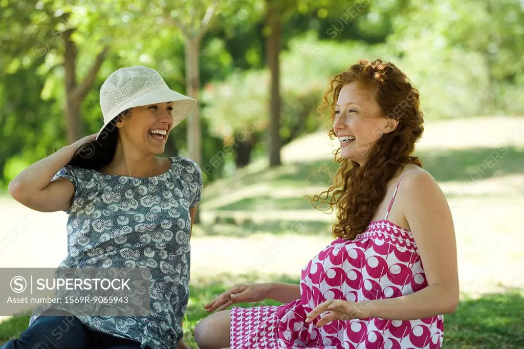 Two young women chatting outdoors, both smiling