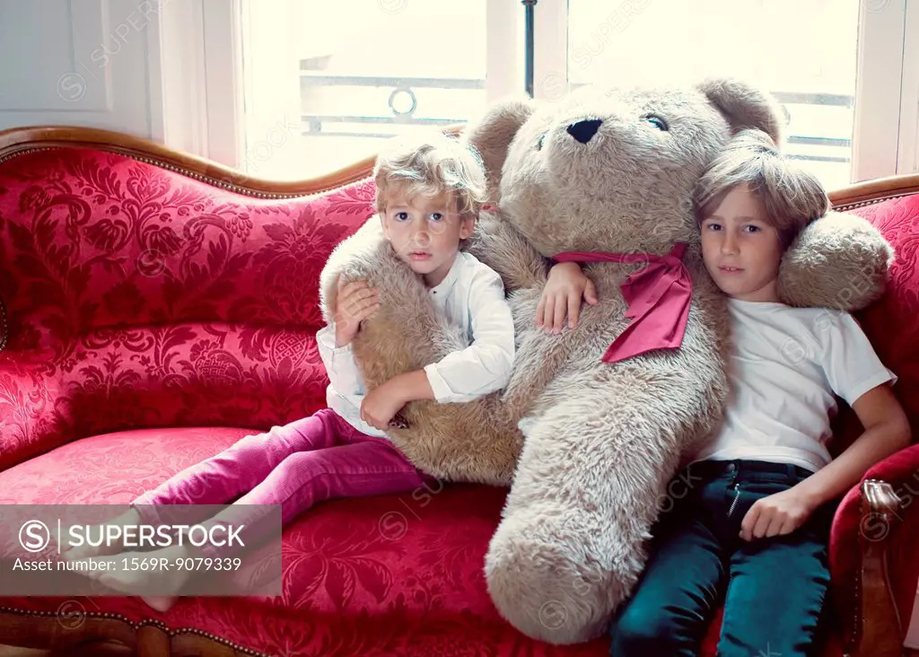 Young brothers embracing large teddy bear, portrait