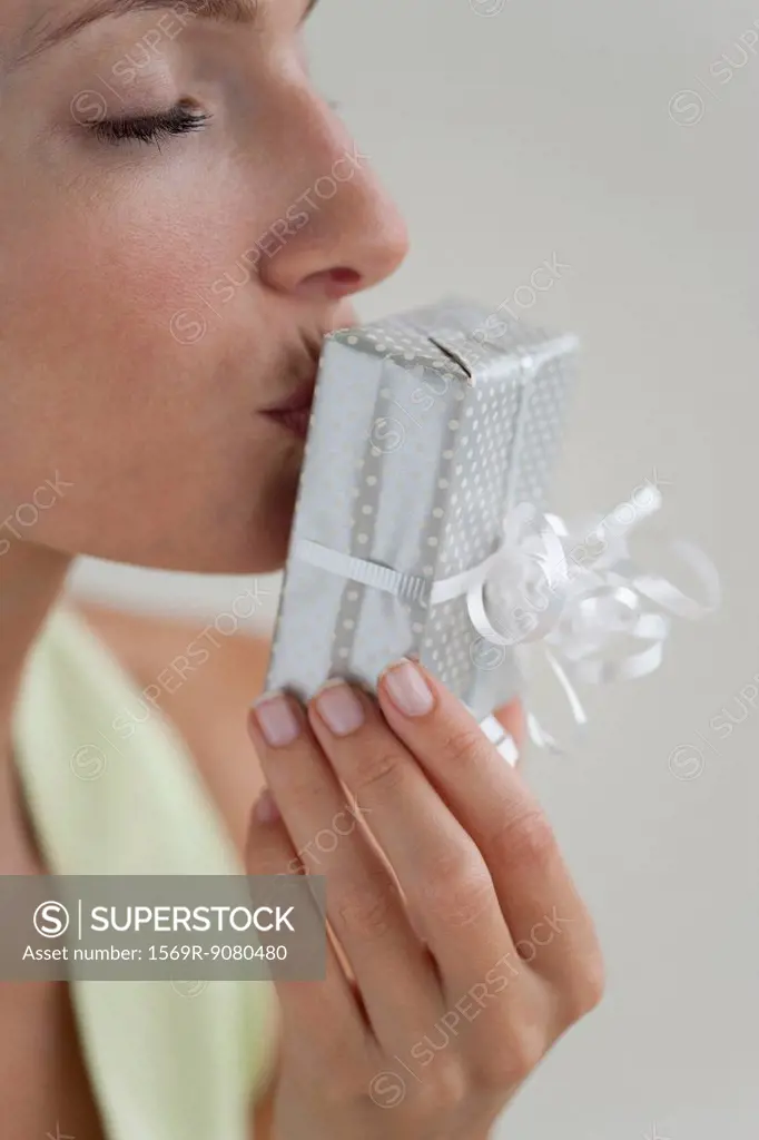 Young woman kissing gift, eyes closed, side view