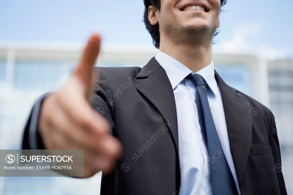 Businessman extending hand for handshake, mid section