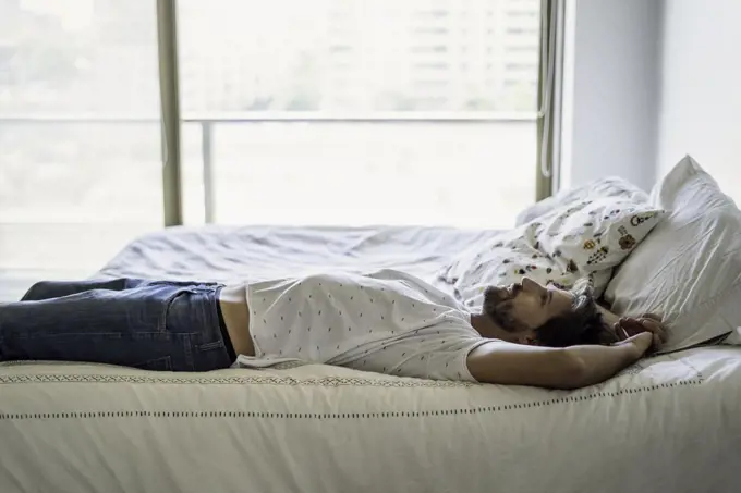 Young man lying on bed