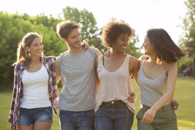 Happy young friends walking together in park