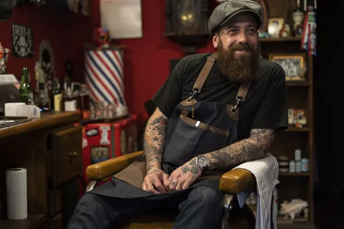 Smiling hairdresser sitting on chair in salon