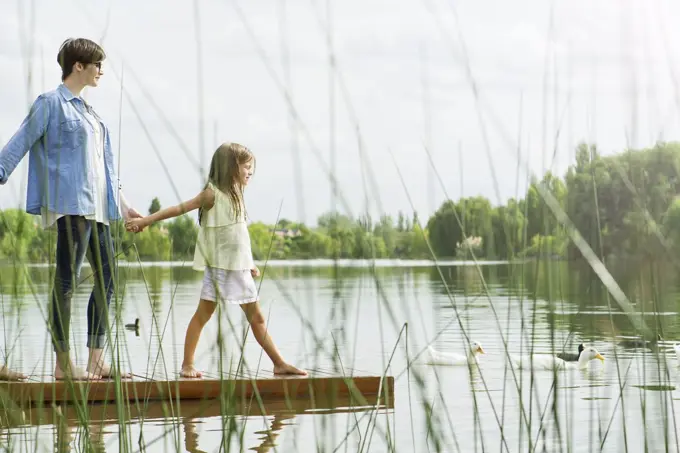 Mother and daughter holding hands on dock