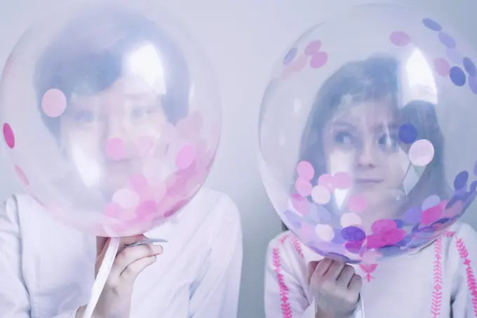 Children hiding behind transparent balloons