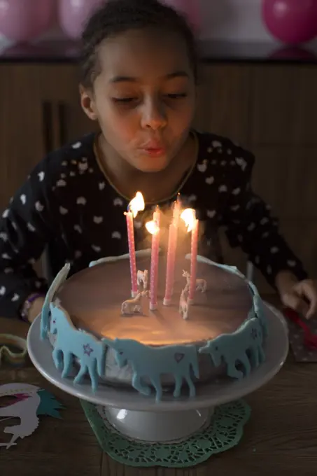 Girl blowing out candles on birthday cake