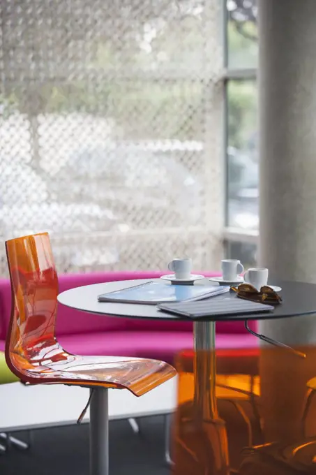 Coffee cups, notebooks, and sunglasses left on table in cafe