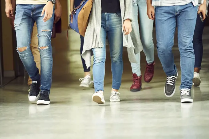 Students walking in school corridor, low section