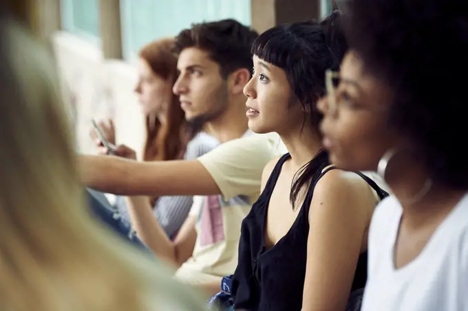 Students sitting in a row, looking up attentively