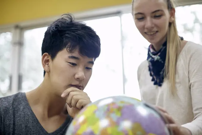 Students looking at globe in classroom