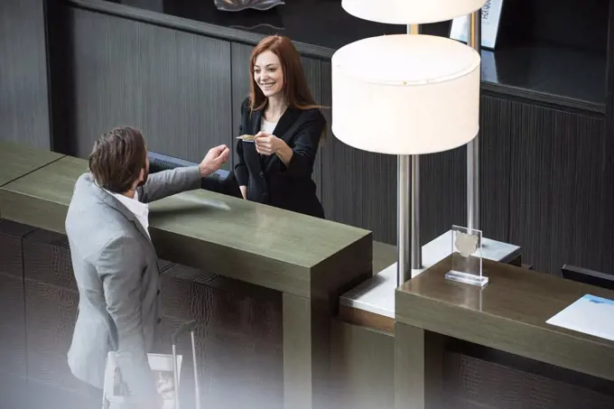 Female receptionist giving credit card to businessman