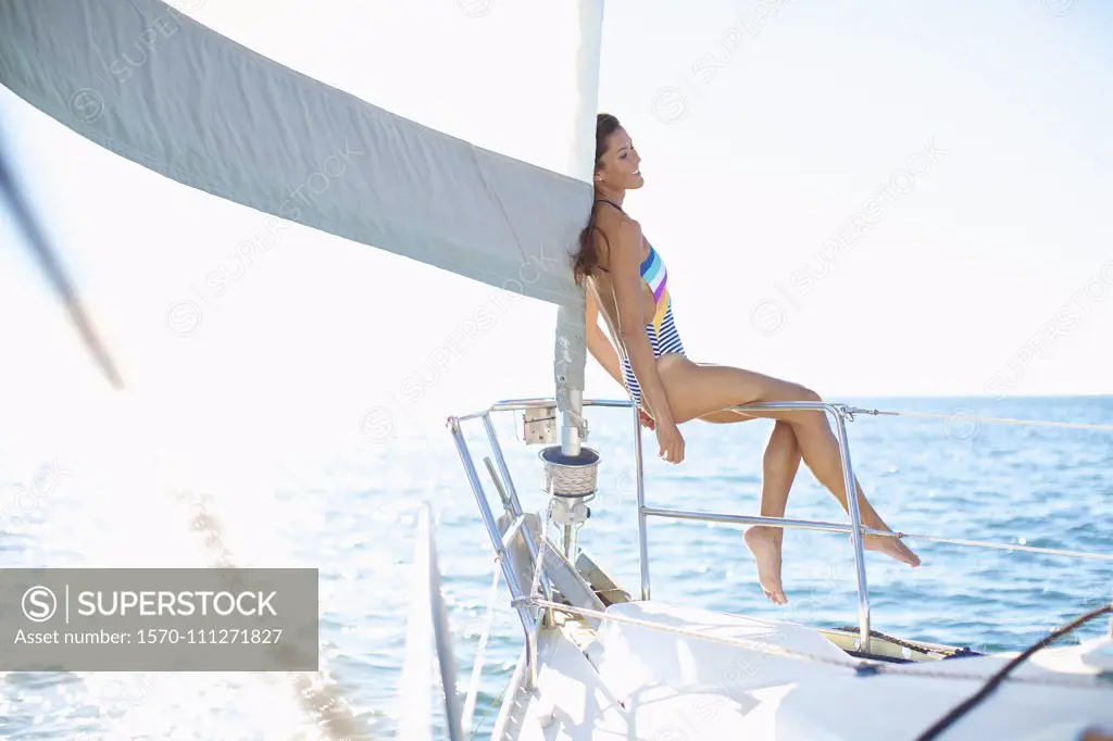 Carefree woman in bathing suit on sunny sailboat