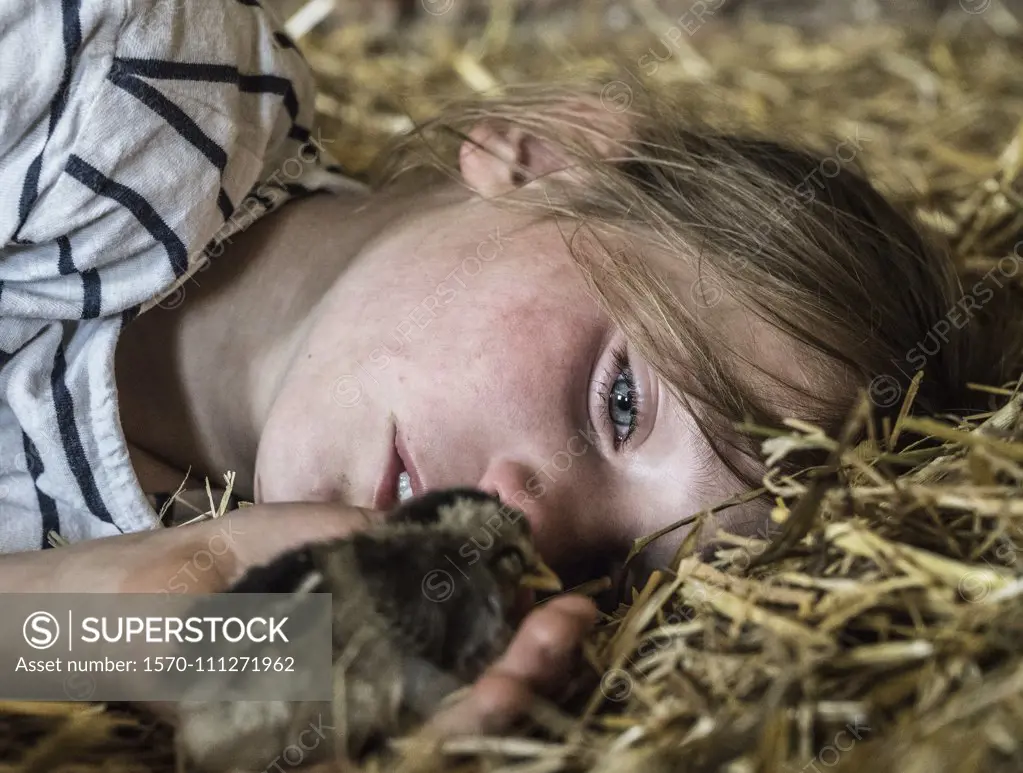 Close up girl holding baby chick in straw