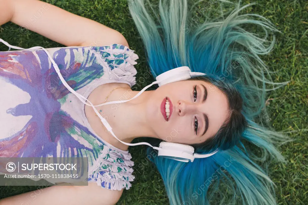 Overhead portrait young woman with blue hair listening to music with headphones