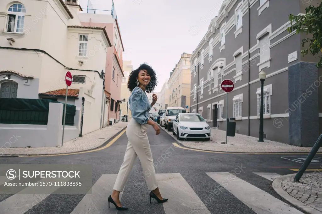 Portrait happy, stylish woman crossing city street