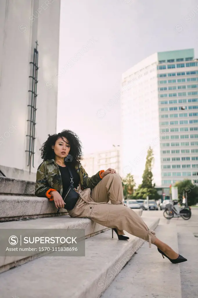 Portrait confident, stylish woman on urban steps