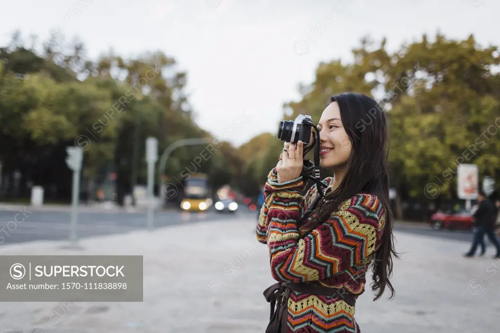 Female tourist using camera on city street