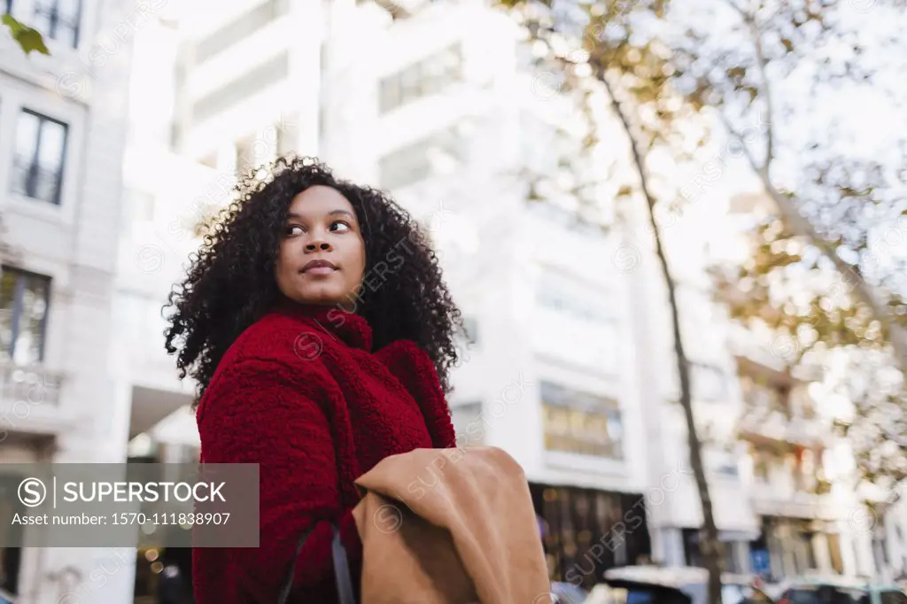 Young woman looking over shoulder on urban street