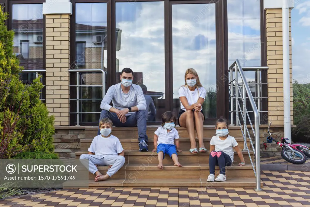 Portrait family in face masks on patio steps of house