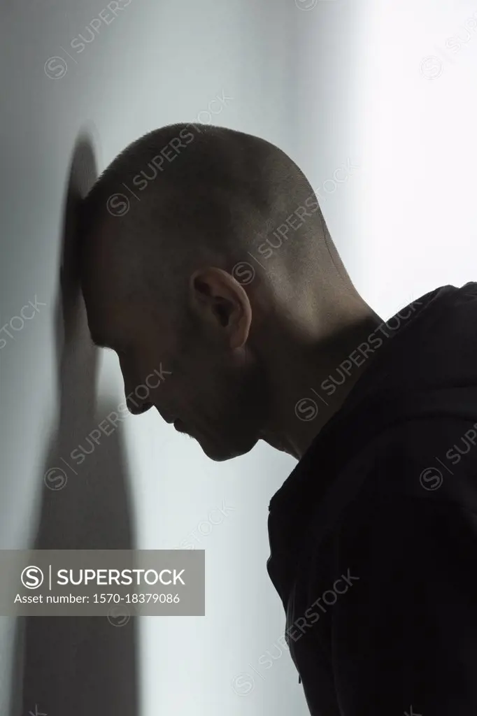 Frustrated man leaning head against wall