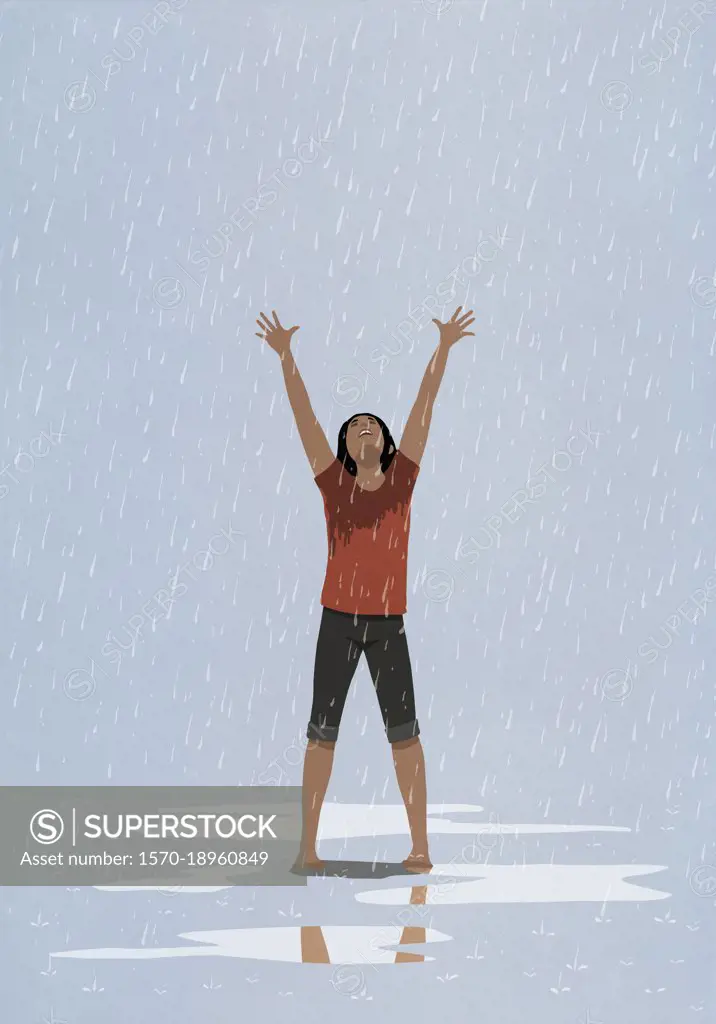 Barefoot, exhilarated woman with arms raised in rain