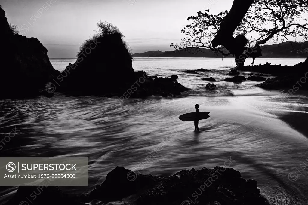 Silhouette boy with surfboard on ocean beach, Sayulita, Nayarit, Mexico