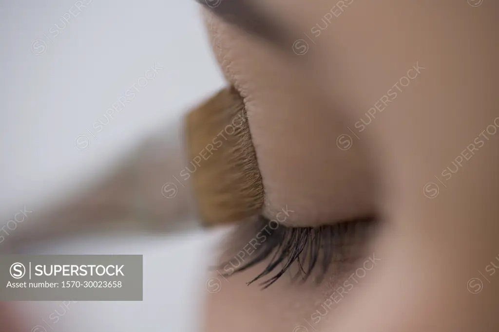 Close up of young woman eye with eyeshadow brush