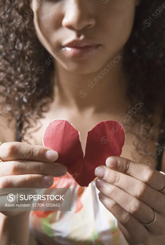 Young woman holding broken heart