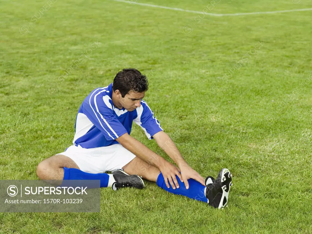 A soccer player stretching on a soccer field
