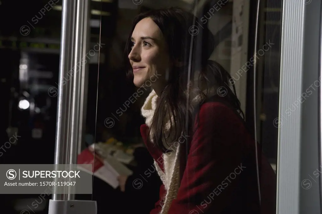 A woman sitting on a subway train smiling