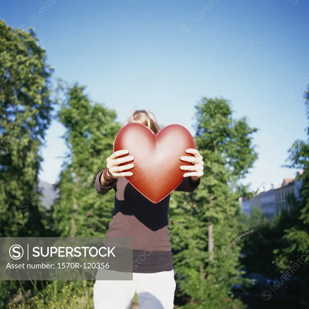 Woman holding a red heart in front of her face