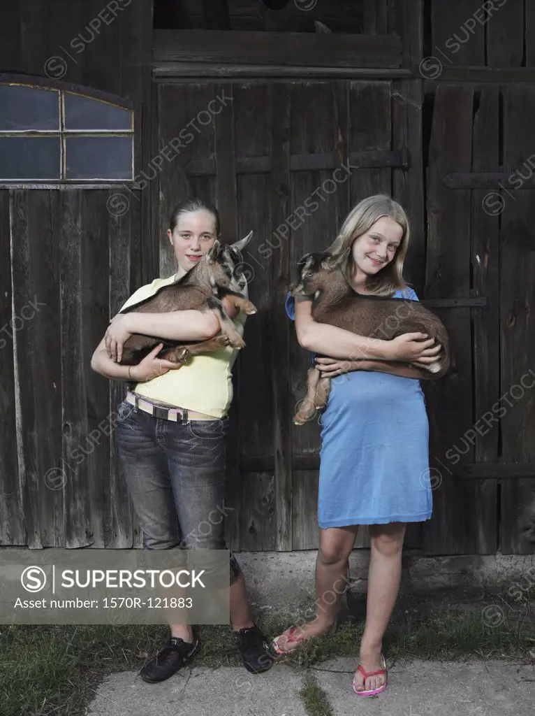 Two girls holding kid goats