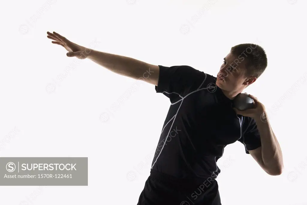 Studio shot of a male track and field athlete holding a shot put ball