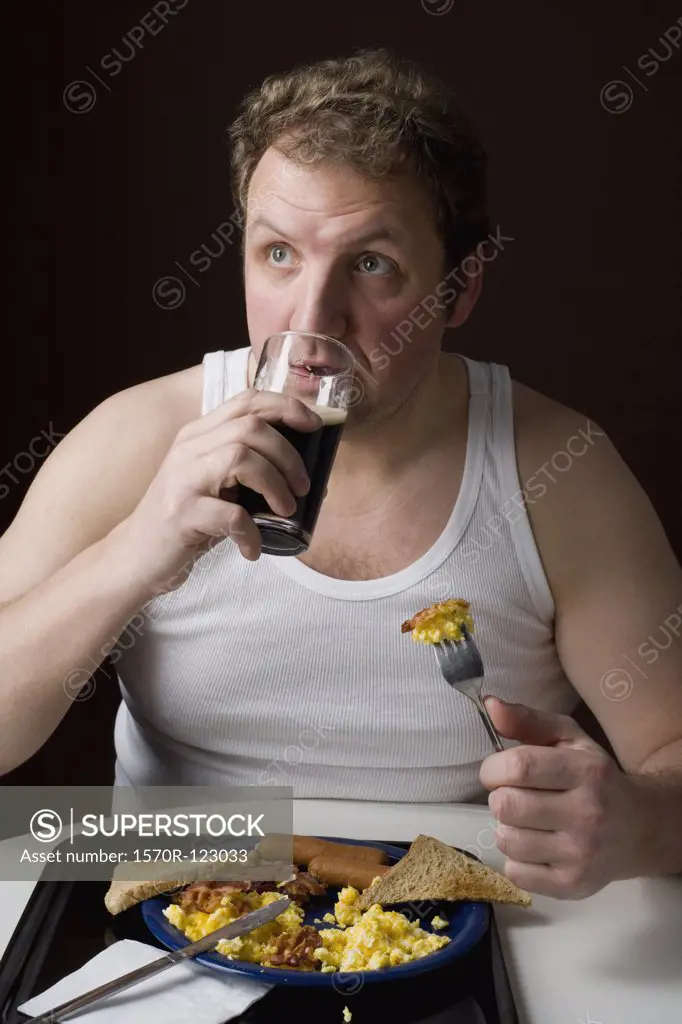 Stereotypical Englishman eating English breakfast and drinking a pint