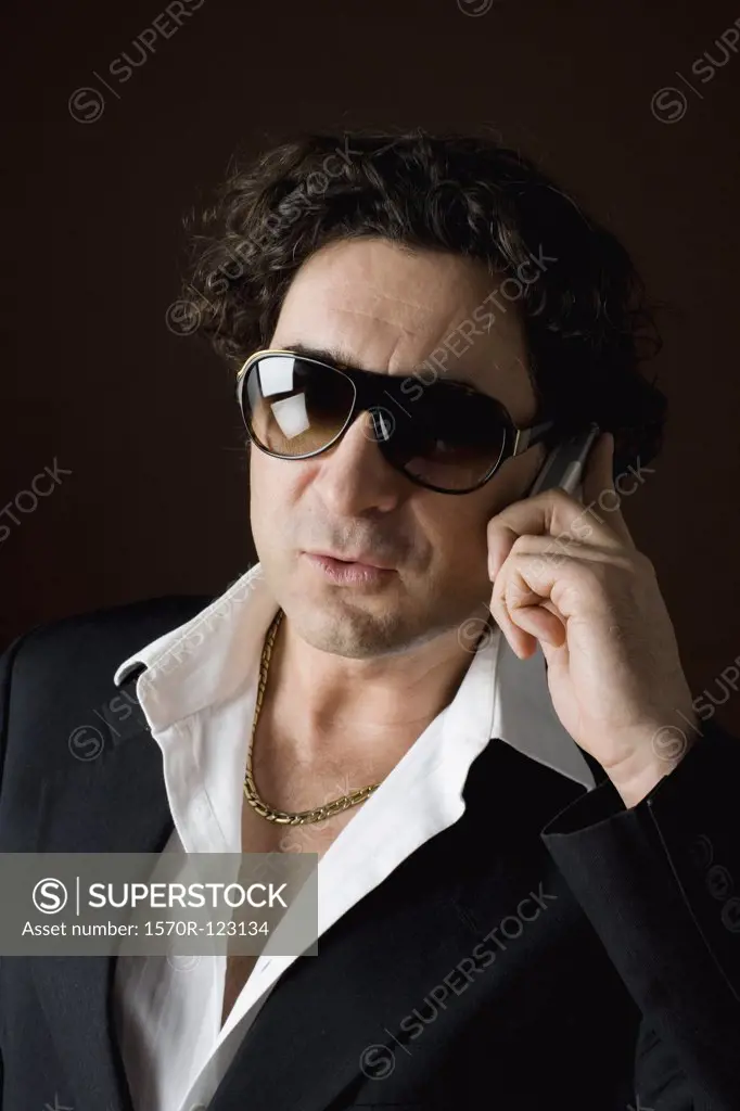 Stereotypical macho, sleazy man talking on a mobile phone