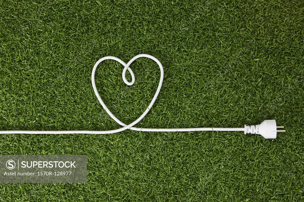 An electrical cord arranged in a heart shape on grass