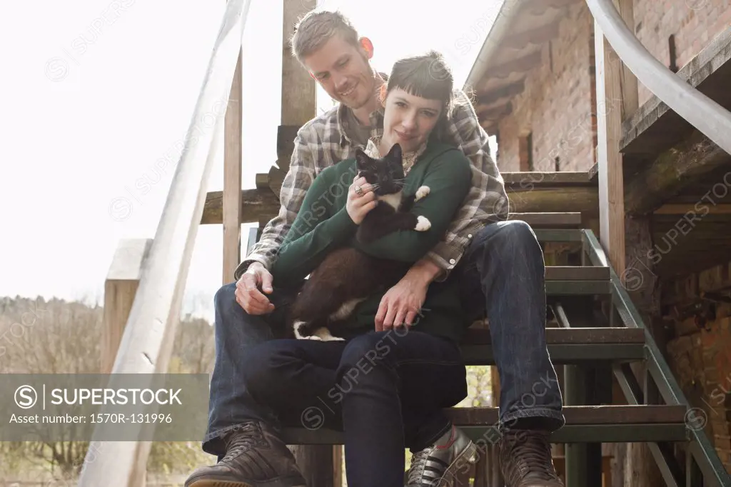 A couple holding and petting a cat