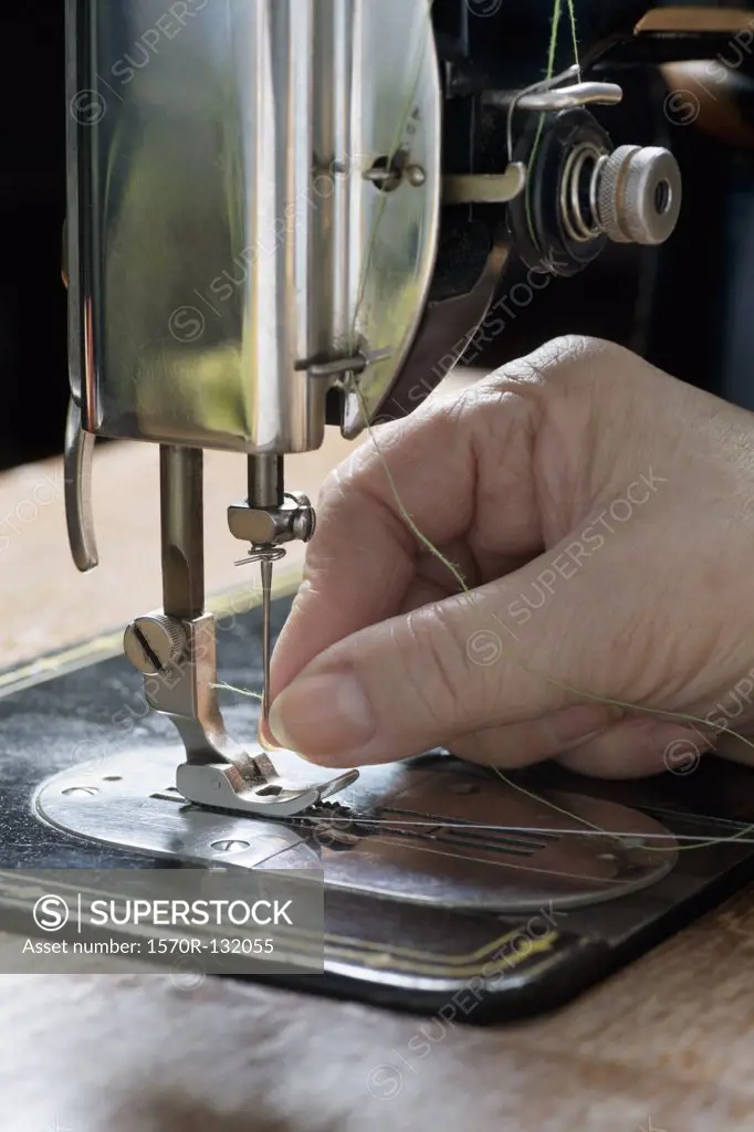 A woman threading a needle on a sewing machine, detail of hand