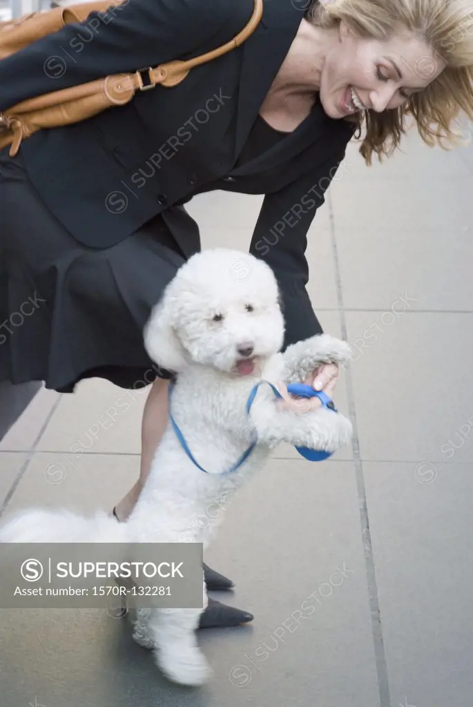 Woman playing with dog on sidewalk