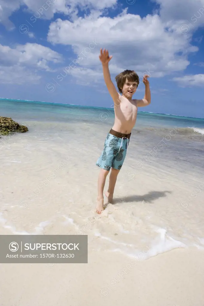 A young boy jumping on the beach, Cable Beach, Nassau, Bahamas, Caribbean