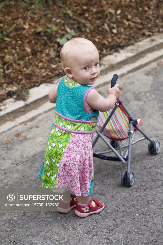 A toddler with a baby stroller