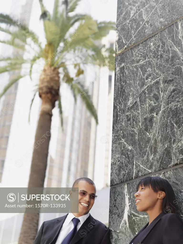 A businessman and businesswoman talking outside an office