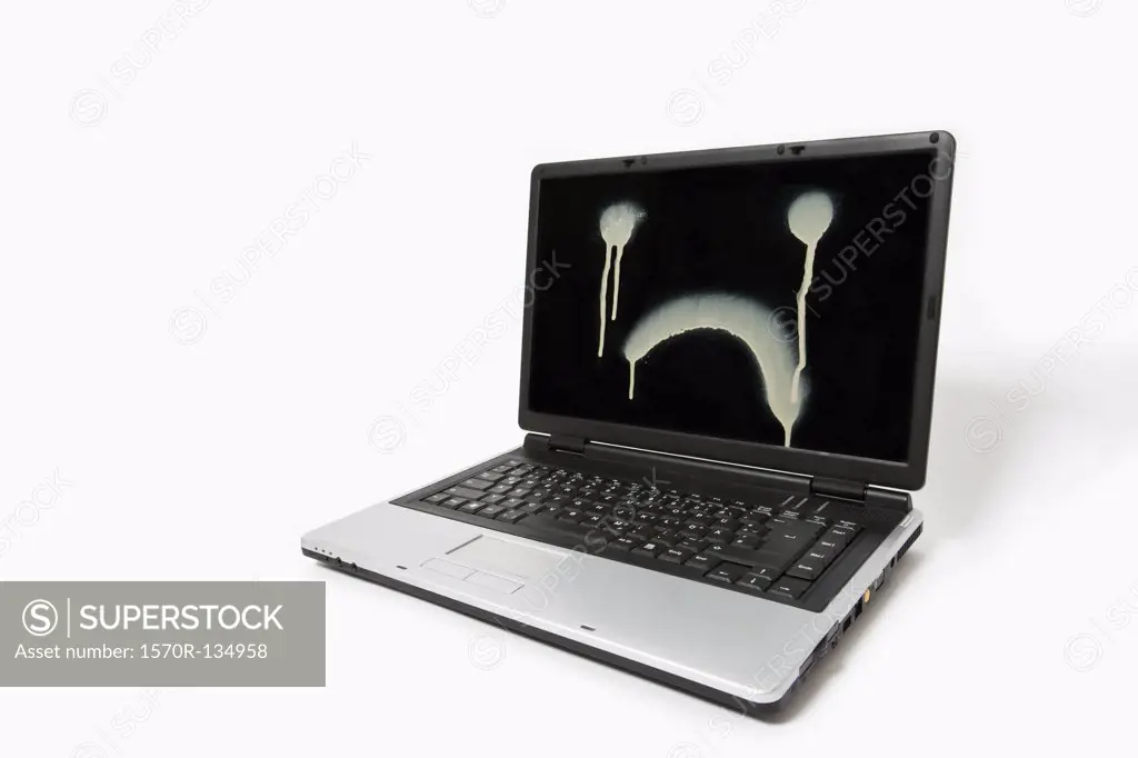 A laptop monitor with a sad face spray painted on it