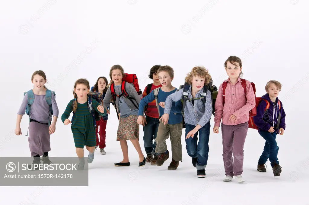 A group of school kids wearing backpacks and running forward