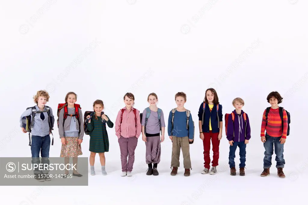 A group of school children wearing backpacks, standing in a row