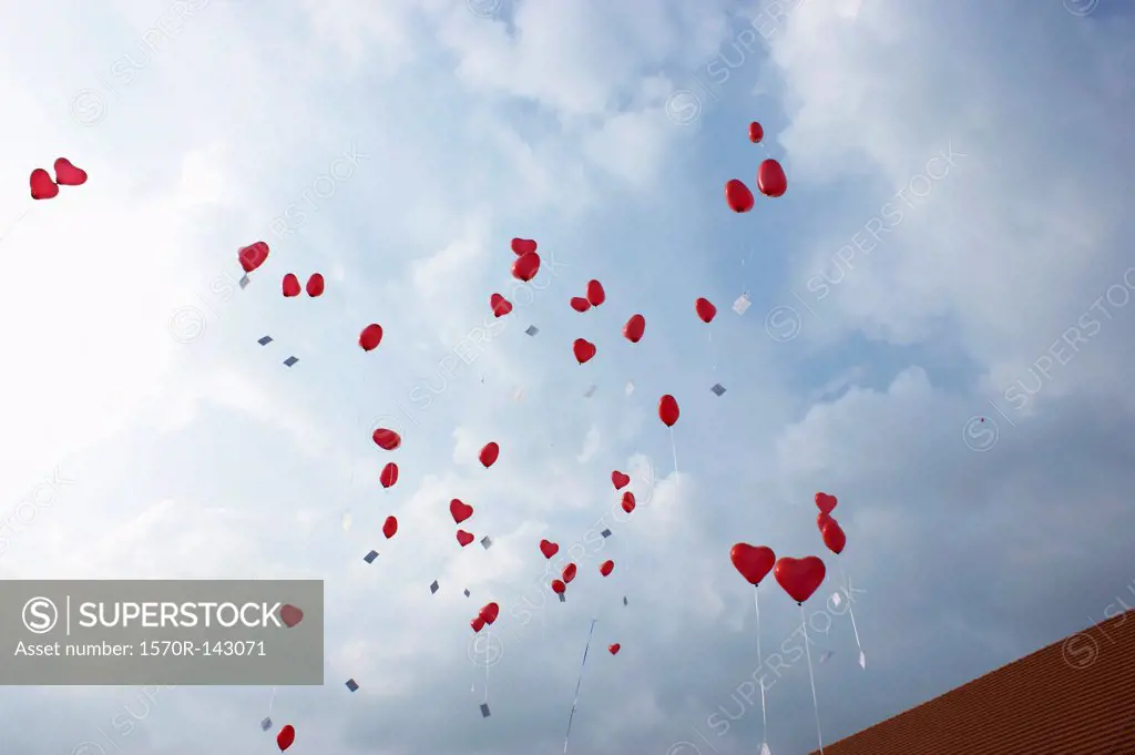 Many red heart shaped helium balloons floating up