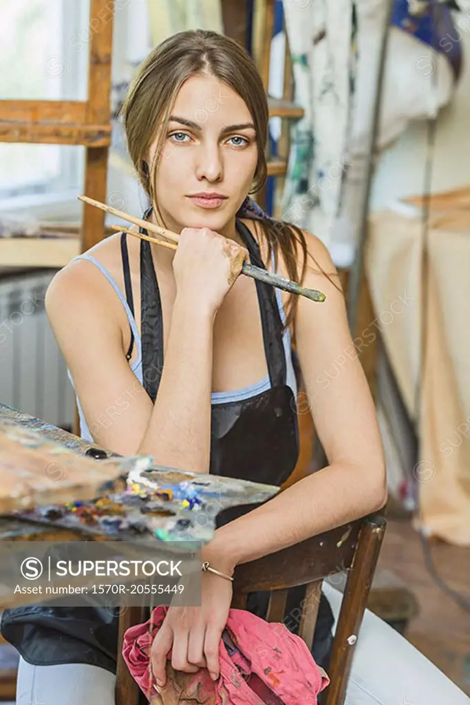 Portrait of beautiful female painter sitting on chair in studio