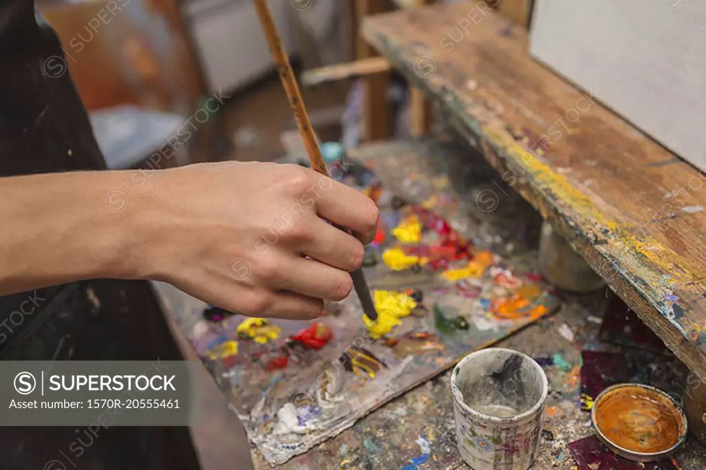 High angle view of artist mixing paint in palette at studio