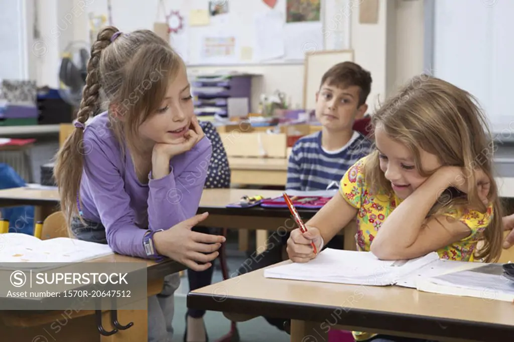 Students writing on book in classroom