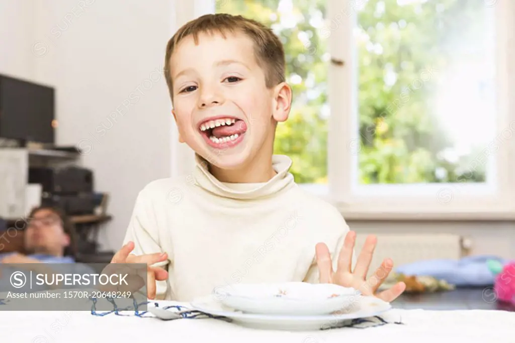 Portrait of cute boy sticking out tongue at table